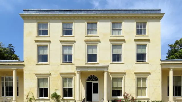 บ้าน Agatha Christie ที่ Greenway ด้านหน้าบ้านจอร์เจียนสามชั้นกับปีกชั้นเดียวสองข้าง ภาพถ่ายเมื่อ 7 กรกฎาคม 2013