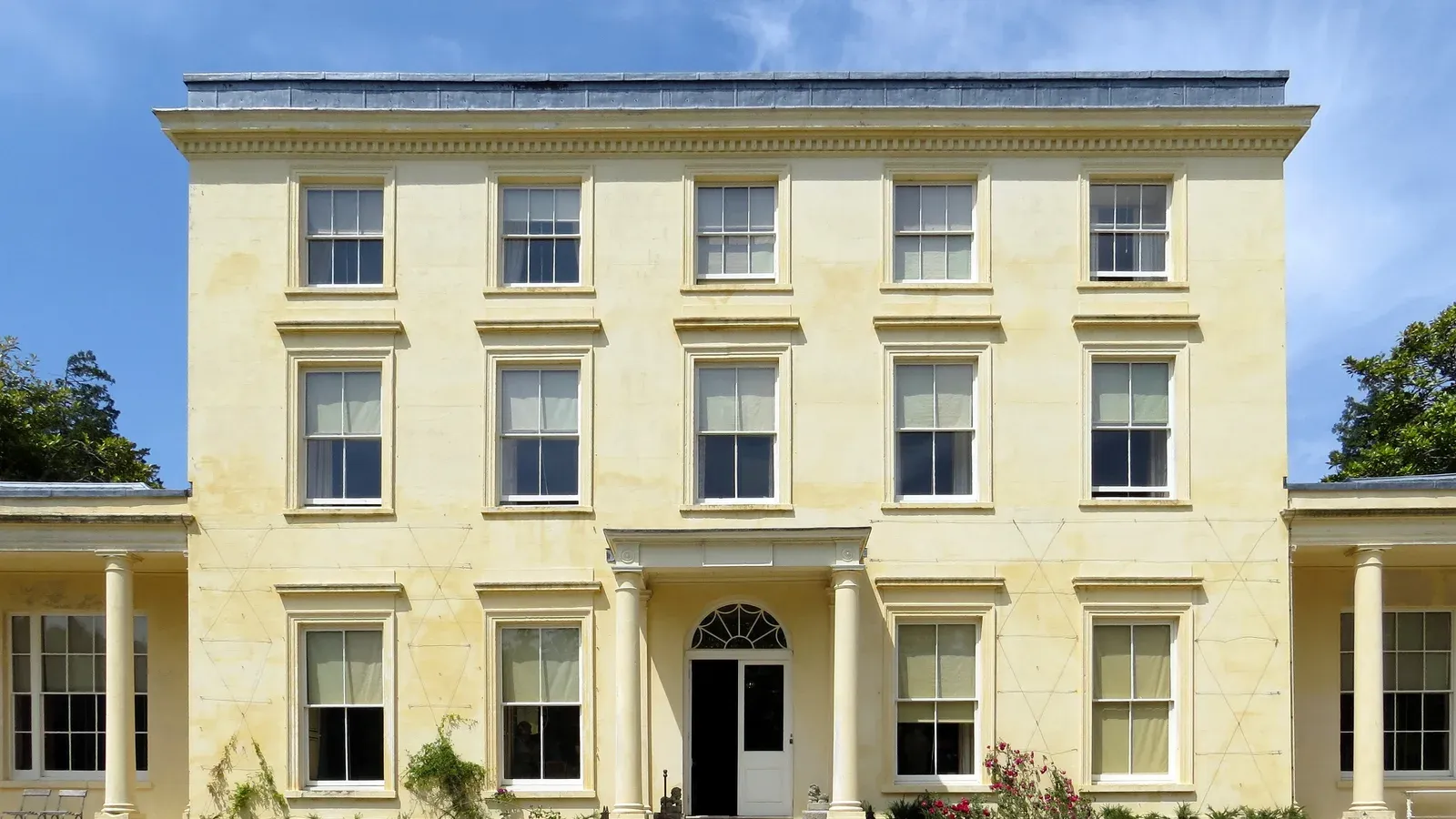 บ้าน Agatha Christie ที่ Greenway ด้านหน้าบ้านจอร์เจียนสามชั้นกับปีกชั้นเดียวสองข้าง ภาพถ่ายเมื่อ 7 กรกฎาคม 2013