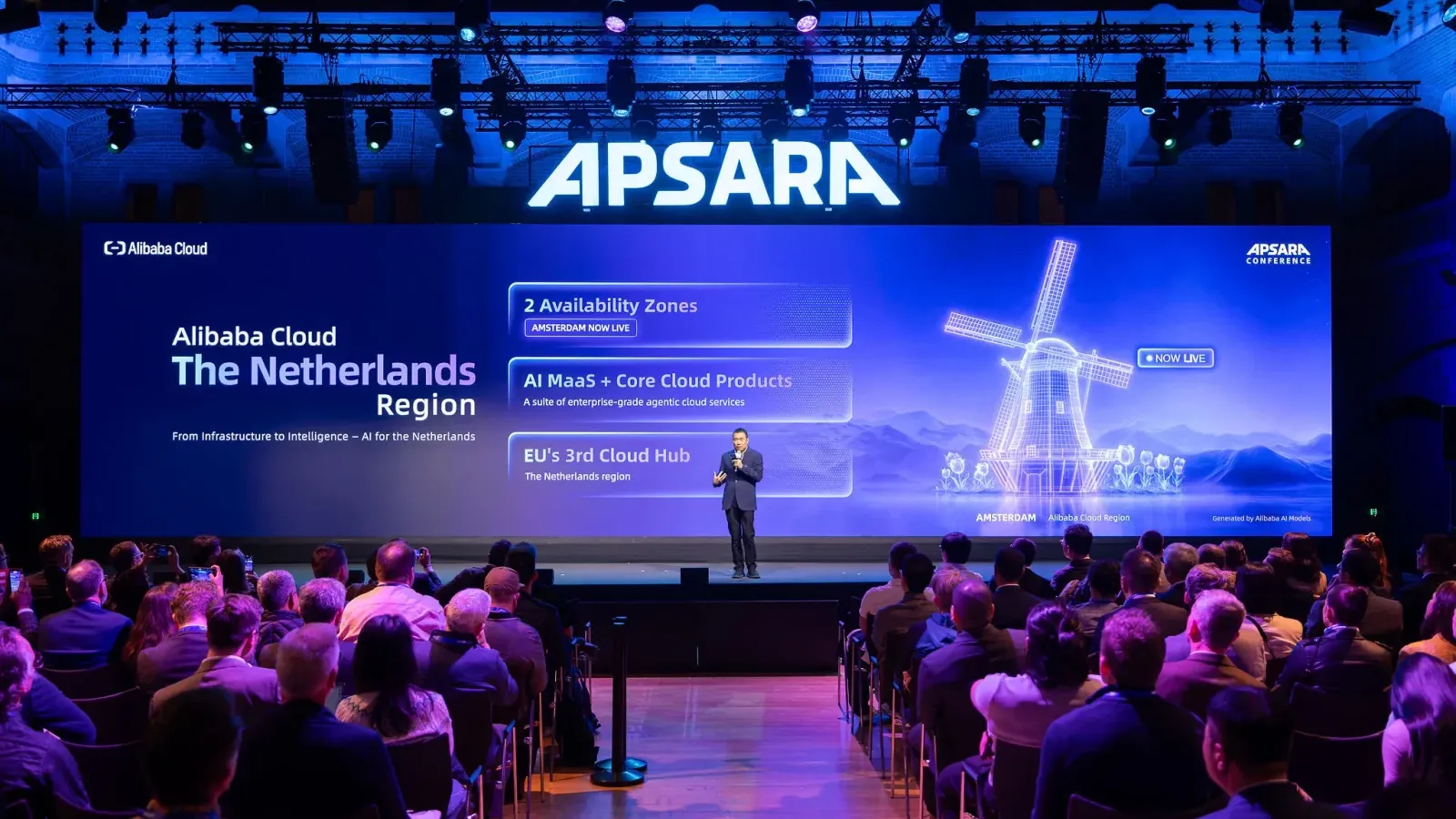 เวที International Apsara Conference ที่อัมสเตอร์ดัม ผู้บรรยายยืนหน้าจอแสดง Alibaba Cloud The Netherlands Region ในการเปิด Alibaba Cloud Amsterdam