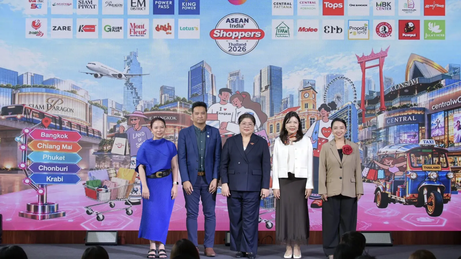 ผู้บริหาร ททท. และพาร์ตเนอร์ยืนบนเวทีเปิดโครงการ ASEAN India+ Shoppers in Thailand 2026 หน้าฉากโลโก้ห้างและแบรนด์ที่ร่วมโครงการ
