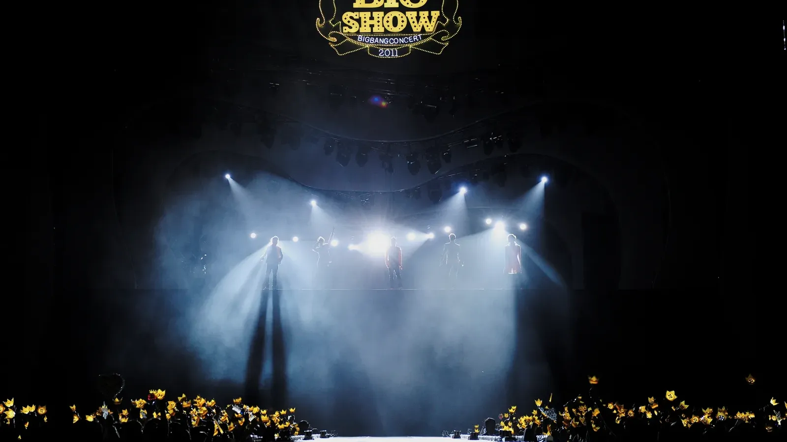 BIGBANG บนเวทีคอนเสิร์ต Big Show ปี 2011 แฟนเพลงชูแท่งไฟมงกุฎสีเหลือง วงที่จะมาคอนเสิร์ต BIGBANG ราชมังคลา 7–8 พ.ย. 2569