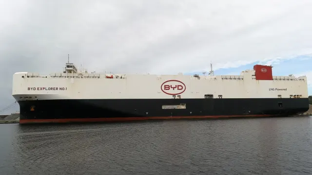 เรือขนส่งรถยนต์ BYD EXPLORER NO.1 ของ BYD จอดเทียบท่าที่ Wilhelmshaven ประเทศเยอรมนี ตัวเรือสีขาวมีโลโก้ BYD และข้อความ LNG Powered