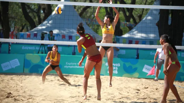 นักวอลเลย์บอลชายหาดหญิงทีมชาติไทยในชุดแข่งสีเหลืองกระโดดบล็อกหน้าตาข่ายในยูธโอลิมปิก 2018 ที่บัวโนสไอเรส ทีมไทยรุ่นเยาวชนที่ไปแข่งยูธโอลิมปิก ดาการ์ 2026 อยู่สาย B