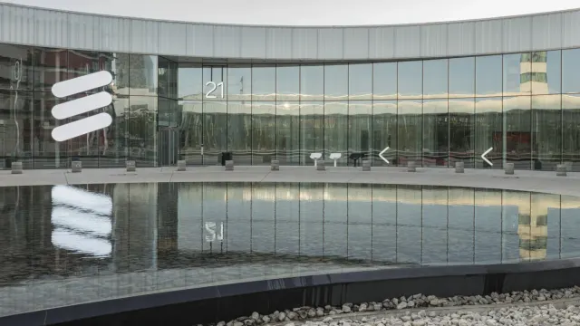 โลโก้ Ericsson บนกระจกด้านหน้าอาคารสำนักงานใหญ่ของ Ericsson สะท้อนลงบนสระน้ำด้านหน้าอาคาร