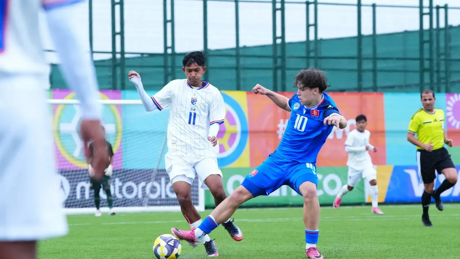 ผู้เล่นทีมชาติไทย U15 หมายเลข 11 ชุดขาว แย่งบอลกับผู้เล่นสโลวาเกียชุดน้ำเงิน ใน FIFA U-15 World Cup 2026 ทีมชาติไทยนัดที่สองที่บากู