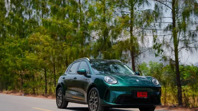 GWM ORA 5 EV สีเขียวเข้ม ป้ายแดงไทย แล่นบนถนนที่มีต้นไม้สองข้าง