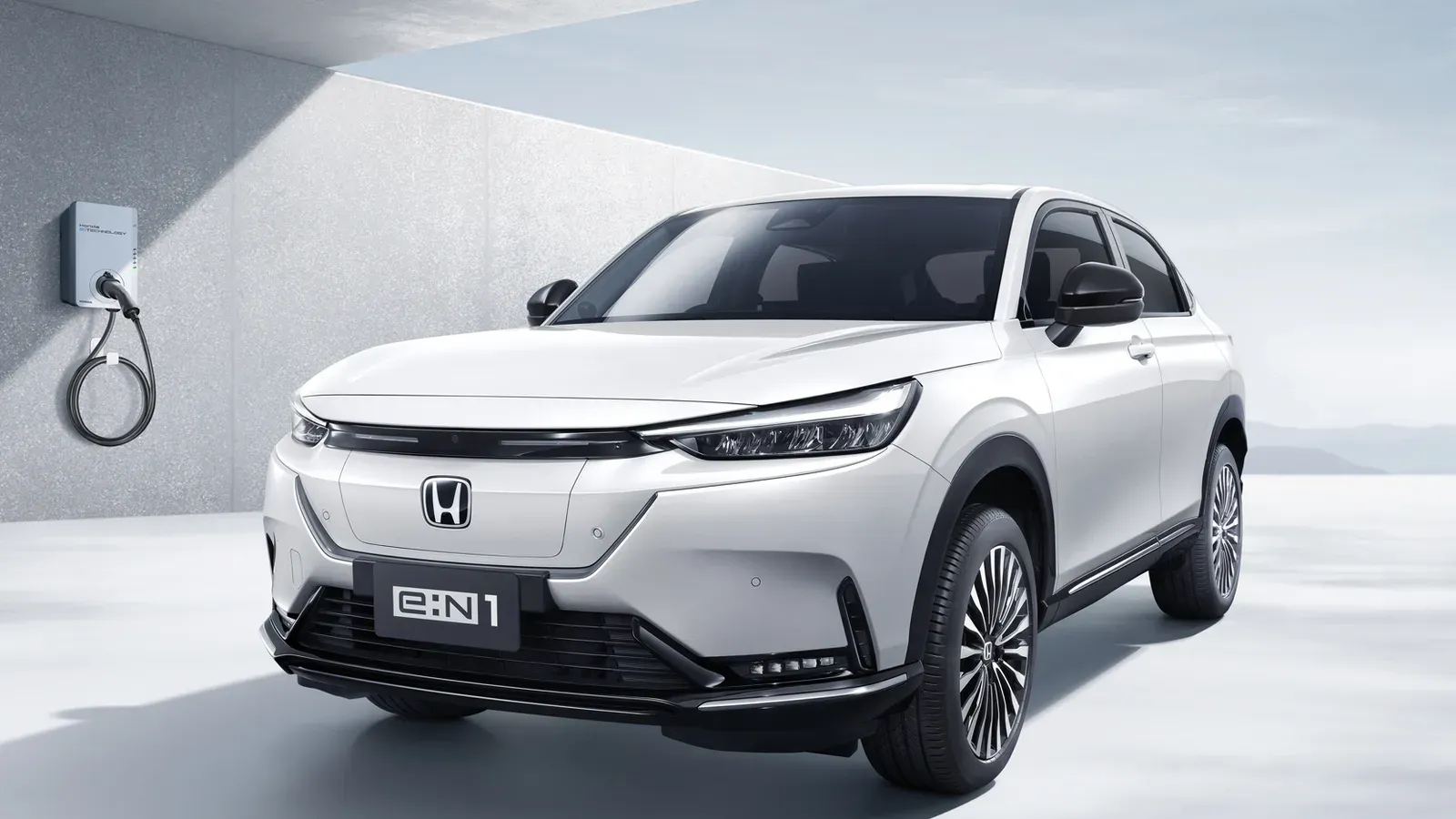 Honda e:N1 สีขาวมุมด้านหน้า จอดข้างเครื่องชาร์จติดผนัง ภาพจากหน้ารุ่นรถของ Honda ประเทศไทย