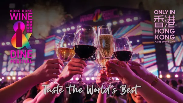 ภาพหลักงาน Wine & Dine ฮ่องกง 2026 (Hong Kong Wine & Dine Festival) แก้วไวน์ชนกันหน้าเวทีริมอ่าววิกตอเรีย พร้อมคำว่า Taste the World's Best