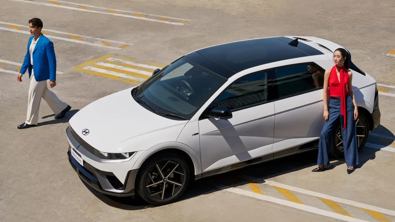 Hyundai The new 2026 IONIQ 5 N Line สีขาว จอดบนลานจอดรถ มีนายแบบและนางแบบยืนข้างรถ ภาพจากหน้าผลิตภัณฑ์ของ Hyundai ประเทศไทย
