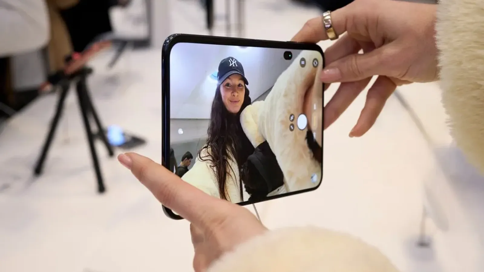 มือผู้ใช้ถือ iPhone Duo ที่กางจอด้านในออก ที่ Apple Fifth Avenue วันวางขาย 23 ตุลาคม 2026 จอด้านในเป็นรายการที่ค่าซ่อม iPhone Duo แพงที่สุด