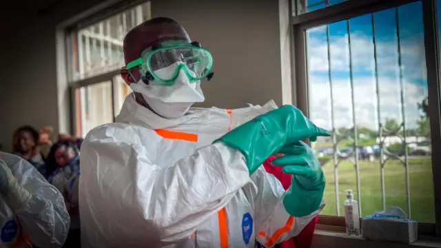 เจ้าหน้าที่สาธารณสุขสวมอุปกรณ์ป้องกันส่วนบุคคล ทั้งแว่นตา หน้ากาก ชุดป้องกัน และถุงมือ ภาพประกอบแถลงการณ์ของ WHO เรื่องผู้ป่วยอีโบลาสายพันธุ์บุนดิบูเกียวรายแรกในเคนยา