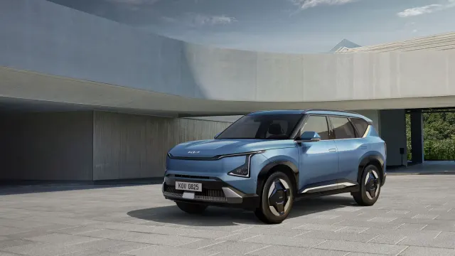 Kia EV5 สีฟ้าอมเทา มองจากมุมหน้าด้านข้าง จอดบนลานหน้าอาคารคอนกรีต ภาพจากแกลเลอรี EV5 ของ Kia ประเทศไทย