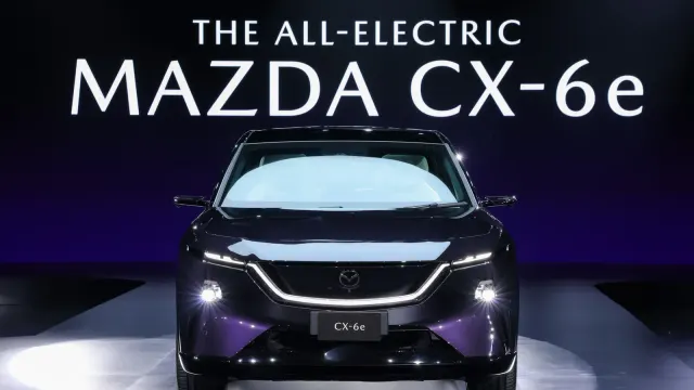Mazda CX-6e มุมด้านหน้าบนเวทีงานเปิดตัวในไทย มีชื่อ THE ALL-ELECTRIC MAZDA CX-6e บนจอด้านหลัง