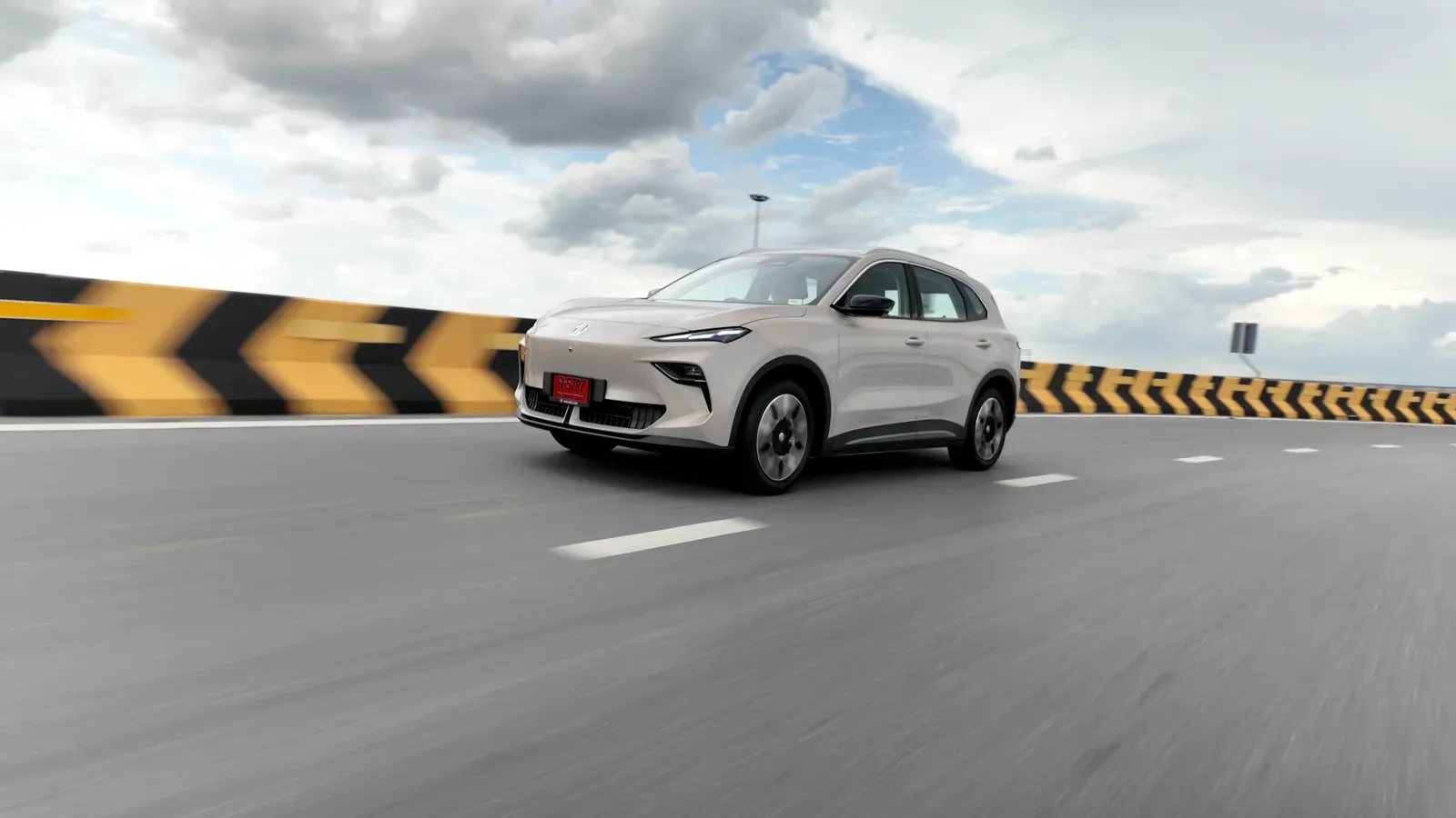 MG S5 EV สีขาวป้ายแดงวิ่งบนถนนที่มีแนวกั้นลายลูกศรสีเหลืองดำ ภาพจาก MG ประเทศไทย