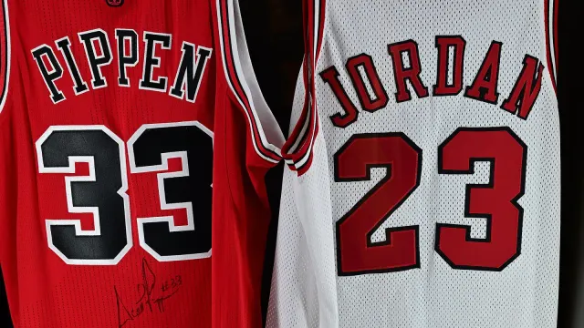 เสื้อแข่ง Chicago Bulls หมายเลข 33 สีแดงของ Scottie Pippen และหมายเลข 23 สีขาวของ Michael Jordan แขวนคู่กัน พร้อมกางเกงขาสั้นและรองเท้าบาสเกตบอล ในตู้จัดแสดงของ Chicago Sports Museum เมื่อกันยายน 2024