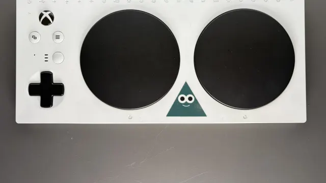 Xbox Adaptive Controller สีขาว ปุ่มกลมขนาดใหญ่สองปุ่มและปุ่มทิศทาง ผลงานที่ถูกพัฒนาต่อในแฮกกาธอนก่อน Microsoft ปิด The Garage