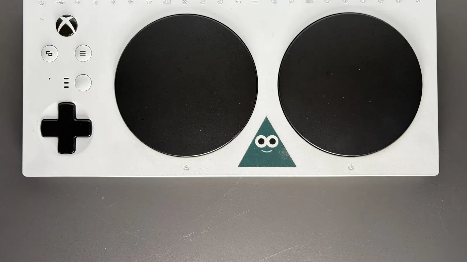 Xbox Adaptive Controller สีขาว ปุ่มกลมขนาดใหญ่สองปุ่มและปุ่มทิศทาง ผลงานที่ถูกพัฒนาต่อในแฮกกาธอนก่อน Microsoft ปิด The Garage