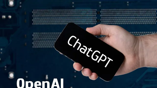 มือถือสมาร์ตโฟนที่แสดงข้อความ ChatGPT พร้อมคำว่า OpenAI บนพื้นหลังแผงวงจร