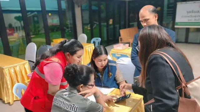 เจ้าหน้าที่ช่วยชาวชุมชนบ้านนาในกรอกข้อมูลบนโทรศัพท์ที่จุดรับลงทะเบียน เคลมประกันภัยพิบัติภูเก็ต เทศบาลเมืองป่าตอง