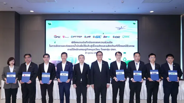 ผู้บริหาร 8 บริษัทกลุ่ม ปตท. ยืนถือแฟ้มบันทึกข้อตกลงความร่วมมือเรื่องน้ำมันพืชใช้แล้ว SAF และปิโตรเคมีชีวภาพ หน้าจอโลโก้ GPSC PTTEP ptt GC IRPC OR และ GGC