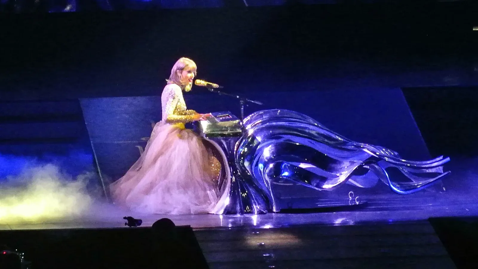 Taylor Swift ในชุดกระโปรงยาวสีชมพูอ่อนเล่นเปียโนบนเวทีช่วงเพลง Wildest Dreams และ Enchanted ในคอนเสิร์ต The 1989 World Tour ที่ STAPLES Center เมือง Los Angeles วันที่ 22 สิงหาคม 2015
