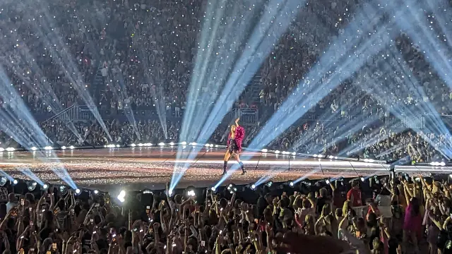 Taylor Swift ในแจ็กเก็ตพู่สีชมพูช่วง Midnights โบกมือให้ผู้ชมบนเวทีรูปเพชรของ The Eras Tour ที่สนาม U.S. Bank Stadium มินนีแอโพลิส 24 มิถุนายน 2023