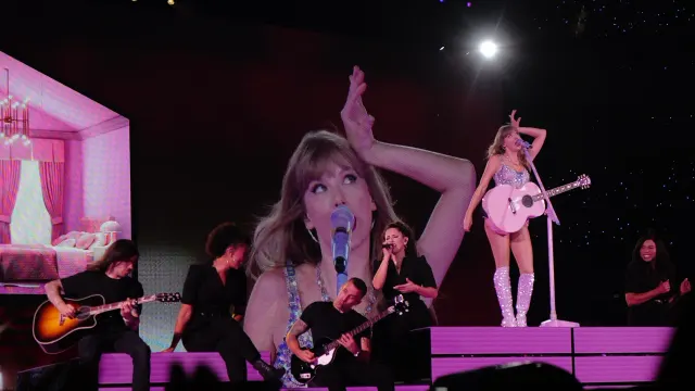 Taylor Swift ถือกีตาร์สีชมพูบนเวทีช่วง Lover ของคอนเสิร์ต The Eras Tour ที่ SoFi Stadium เมือง Inglewood 9 สิงหาคม 2023 โดยมีภาพของเธอบนจอขนาดใหญ่ด้านหลังวงดนตรี