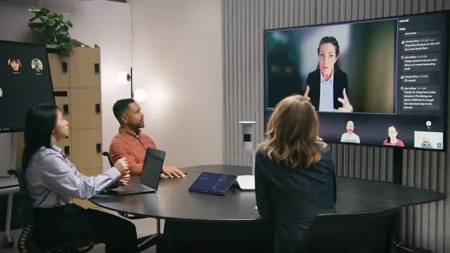 ผู้ร่วมประชุมในห้อง Microsoft Teams Rooms มองจอที่แสดงผู้เข้าร่วมทางไกลและแชต