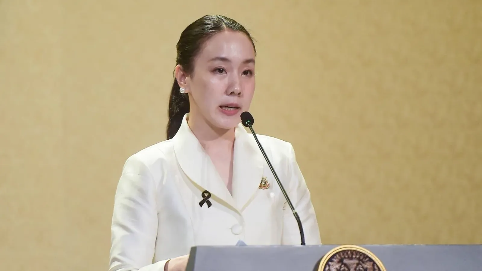 รองโฆษกประจำสำนักนายกรัฐมนตรียืนแถลงหลังโพเดียมที่มีตราสัญลักษณ์รัฐบาล ภาพประกอบประกาศยอดใช้จ่ายไทยช่วยไทย พลัส 60/40 เพิ่มเติม วันที่ 18 ตุลาคม 2569