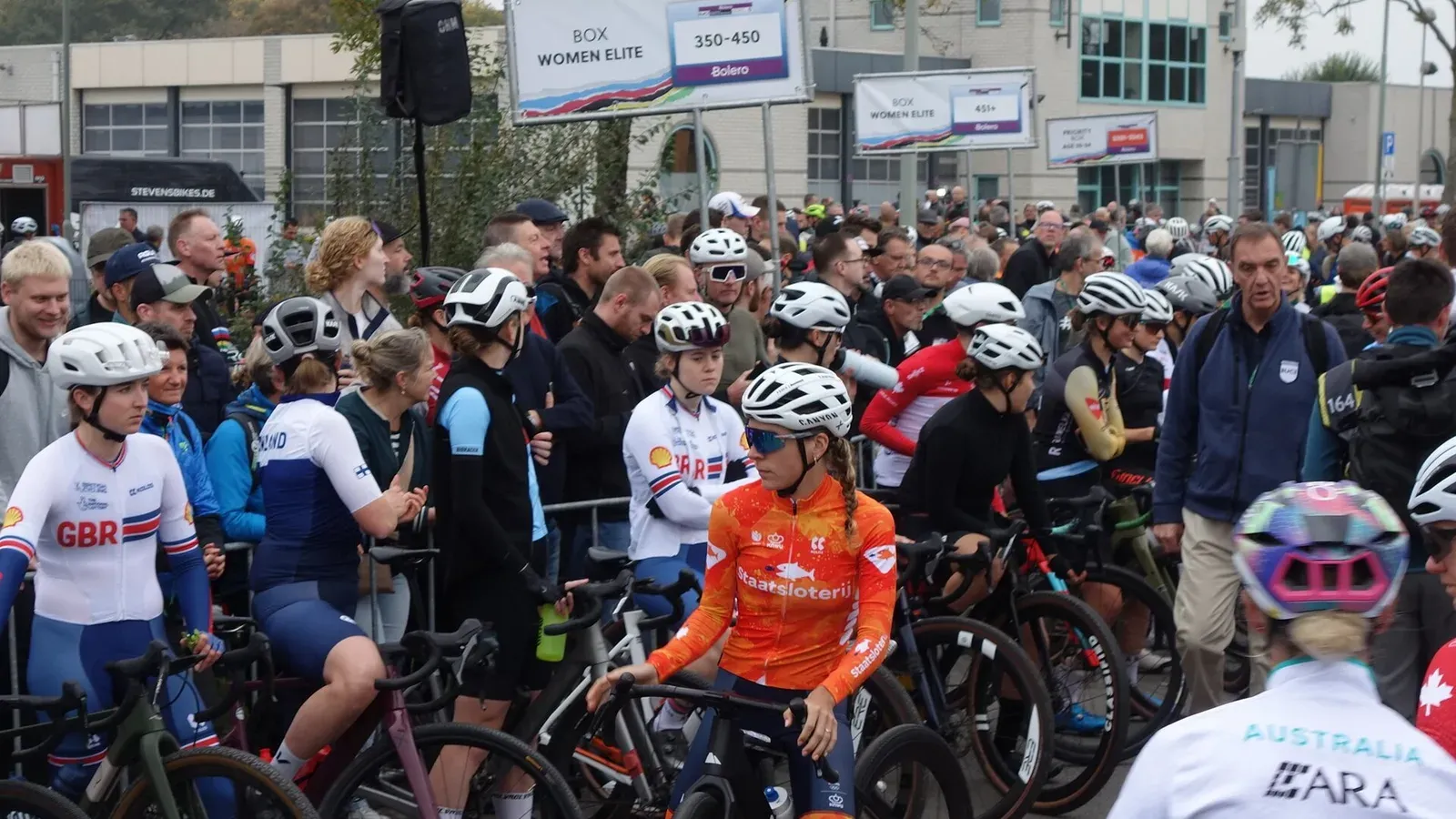 นักปั่นหญิงรุ่น Elite พร้อมจักรยานกราเวลในกล่องปล่อยตัวของ Gravel World Championships 2025 ที่ภาคใต้ของจังหวัดลิมเบิร์ก เนเธอร์แลนด์ มีป้าย BOX WOMEN ELITE อยู่ด้านหลัง