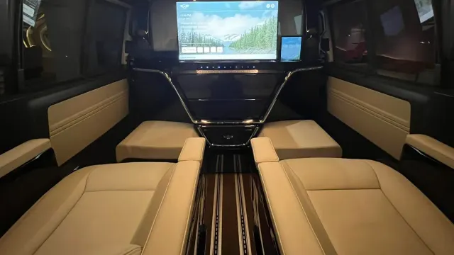 ห้องโดยสารรถตู้ VIP ดัดแปลง Volkswagen Thaiyarnyon Caravelle Comfortline NGZ มองไปทางกระจกกั้นที่มีจอและแท็บเล็ต เบาะหนังสีครีม และพื้นราง Smart Floor
