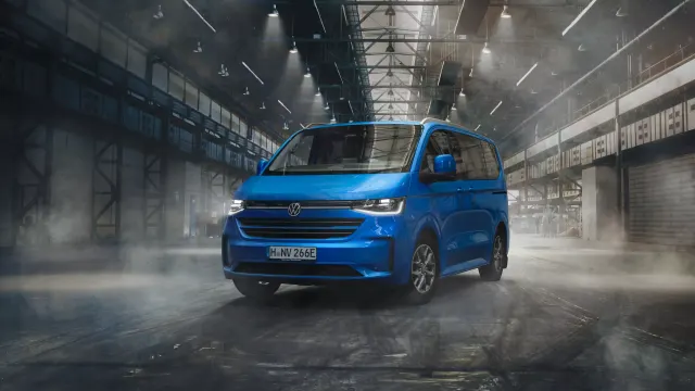 Volkswagen Caravelle T7 หรือ Caravelle รุ่นใหม่ปี 2024 สีน้ำเงิน จอดในโถงอาคารโรงงานเก่า มองจากด้านหน้าเฉียง