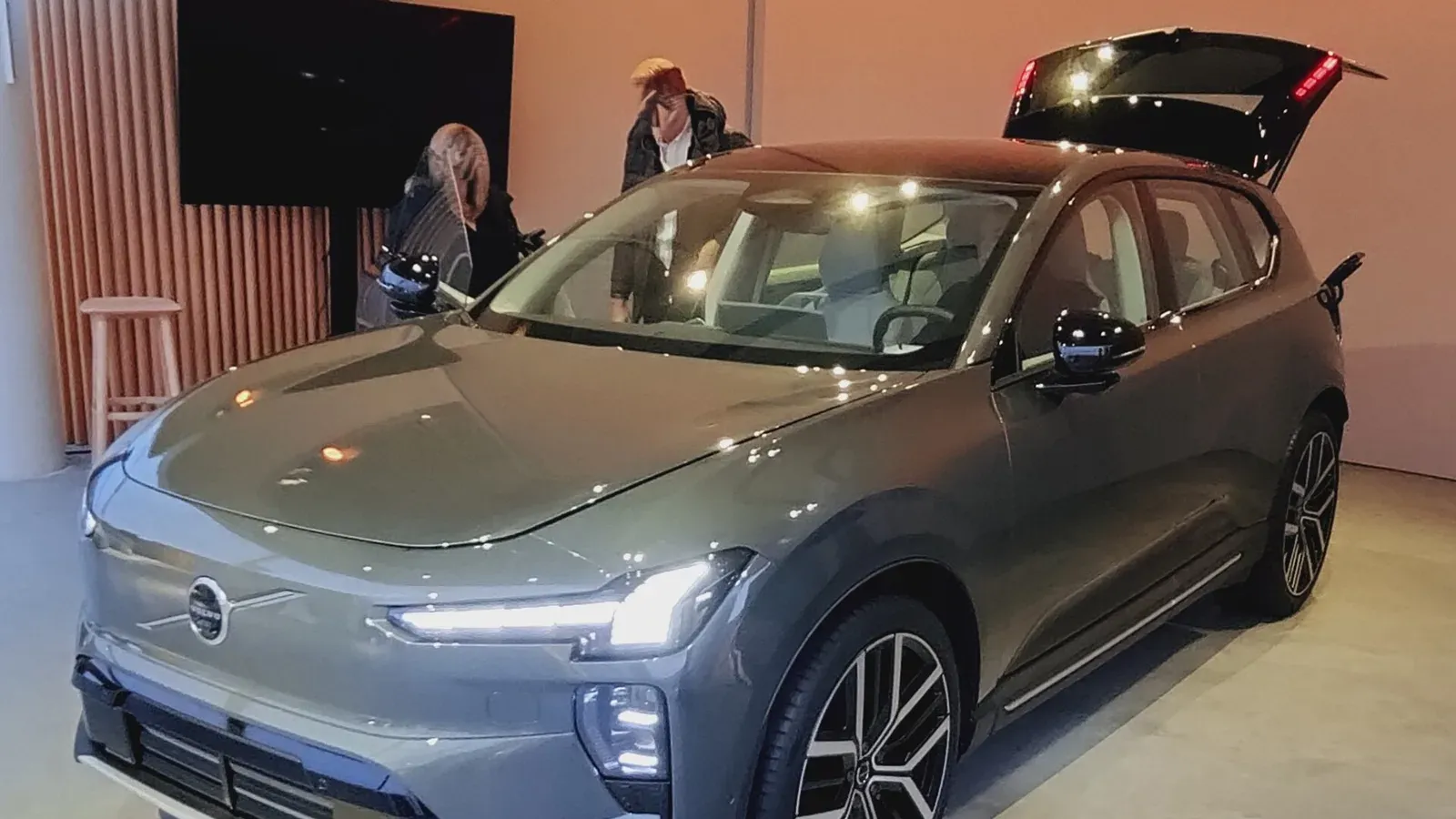 Volvo EX60 สีเทาจัดแสดงในห้องโชว์ เปิดฝาท้าย มีผู้ชมยืนดูด้านหลัง ภาพเดือนมกราคม 2026