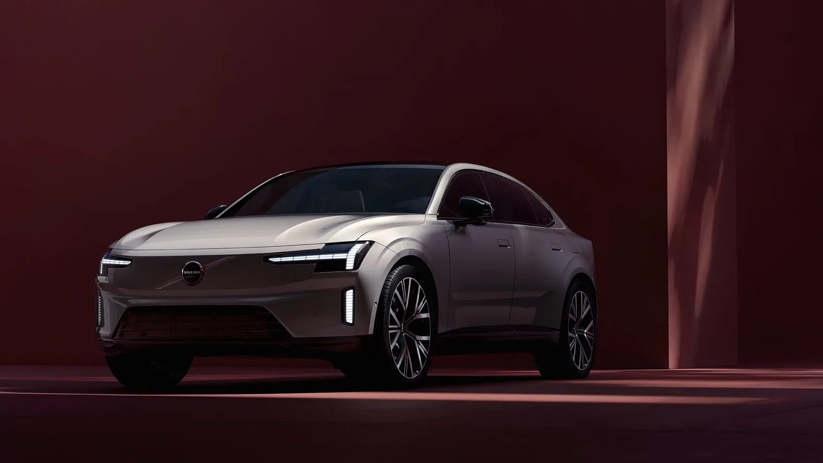 Volvo ES90 สีเทาเงินมุมด้านหน้าเฉียงบนฉากสีแดงเข้ม ภาพจากหน้ารุ่นของ Volvo ประเทศไทย
