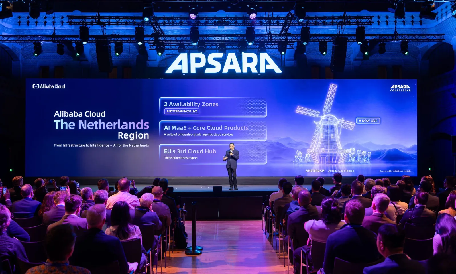เวที International Apsara Conference ที่อัมสเตอร์ดัม ผู้บรรยายยืนหน้าจอแสดง Alibaba Cloud The Netherlands Region ในการเปิด Alibaba Cloud Amsterdam