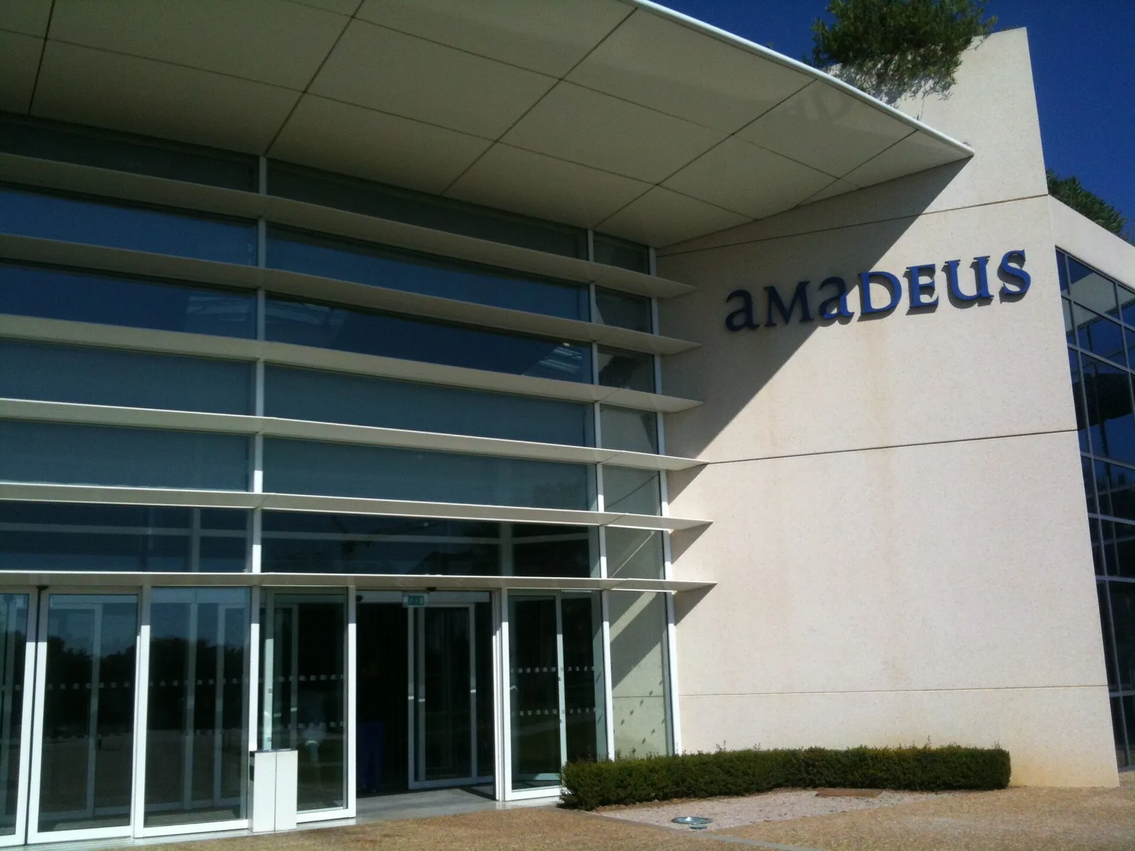 ทางเข้าสำนักงาน Amadeus ในเมืองนีซ ประเทศฝรั่งเศส อาคารกระจกมีชื่อบริษัทบนผนัง