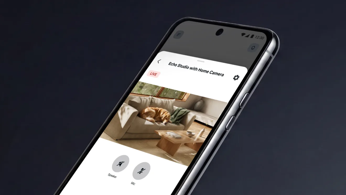 หน้าจอ Live View ของ Echo Studio with Home Camera บนโทรศัพท์ แสดงห้องนั่งเล่นกับสุนัขบนโซฟา