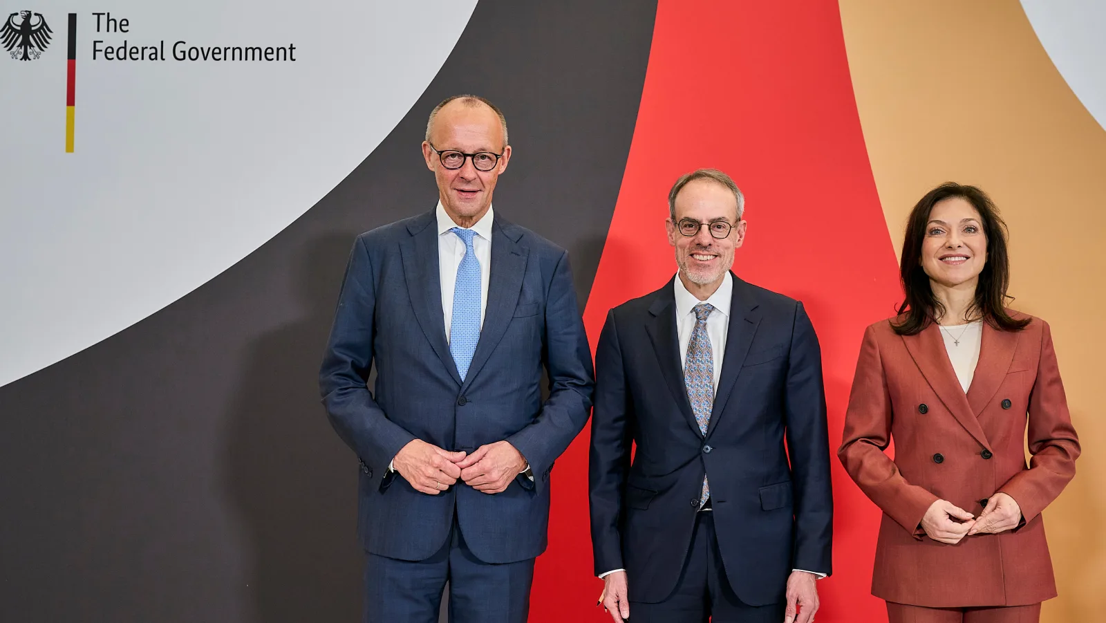 Friedrich Merz นายกรัฐมนตรีเยอรมนี David Zapolsky ของ Amazon และ Katherina Reiche รัฐมนตรีเศรษฐกิจและพลังงาน ยืนหน้าฉากโลโก้รัฐบาลกลางเยอรมนี