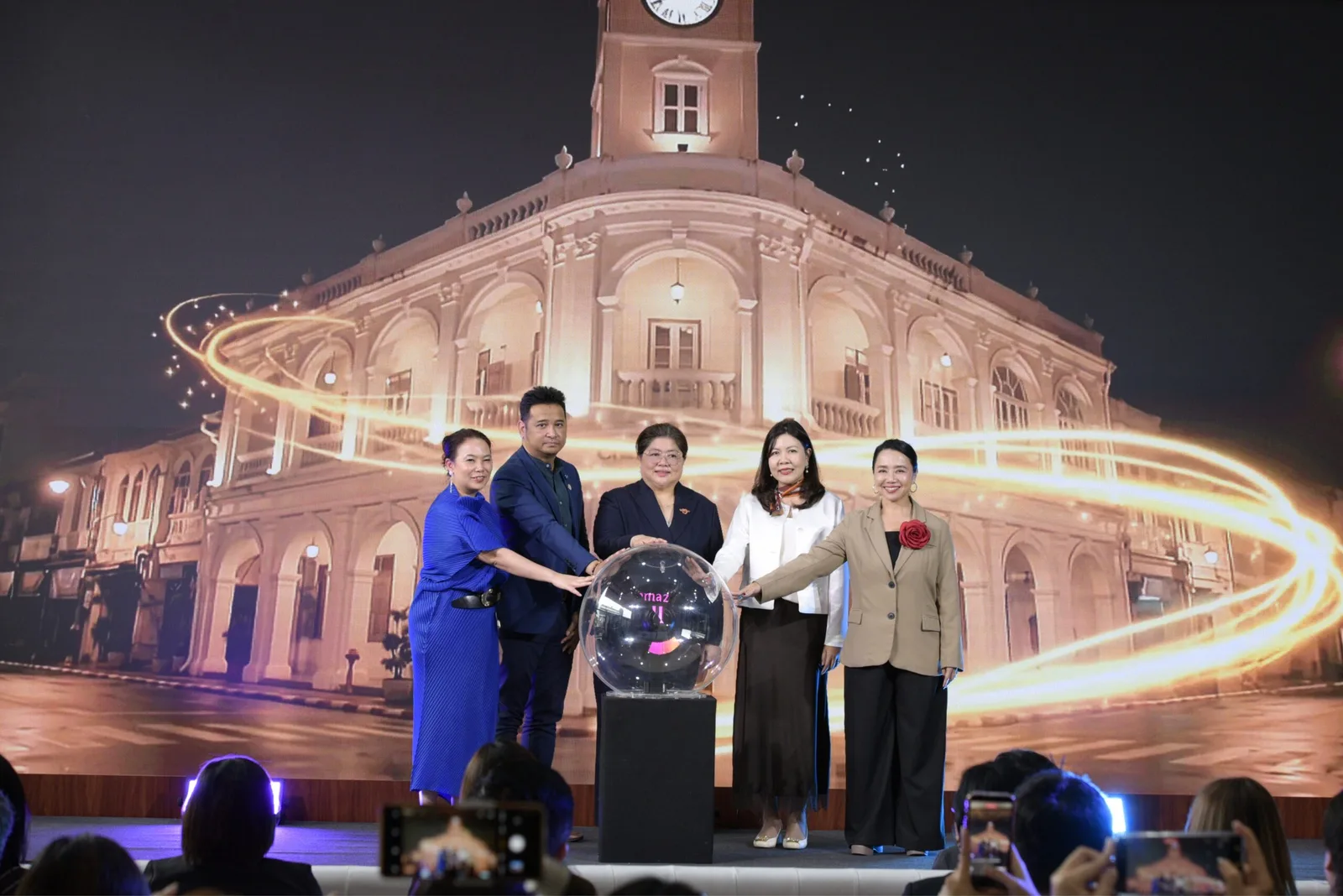 ผู้บริหาร ททท. และพาร์ตเนอร์วางมือบนลูกแก้วเปิดโครงการ Shoppers in Thailand 2026 หน้าจอภาพอาคารเก่าที่มีหอนาฬิกา