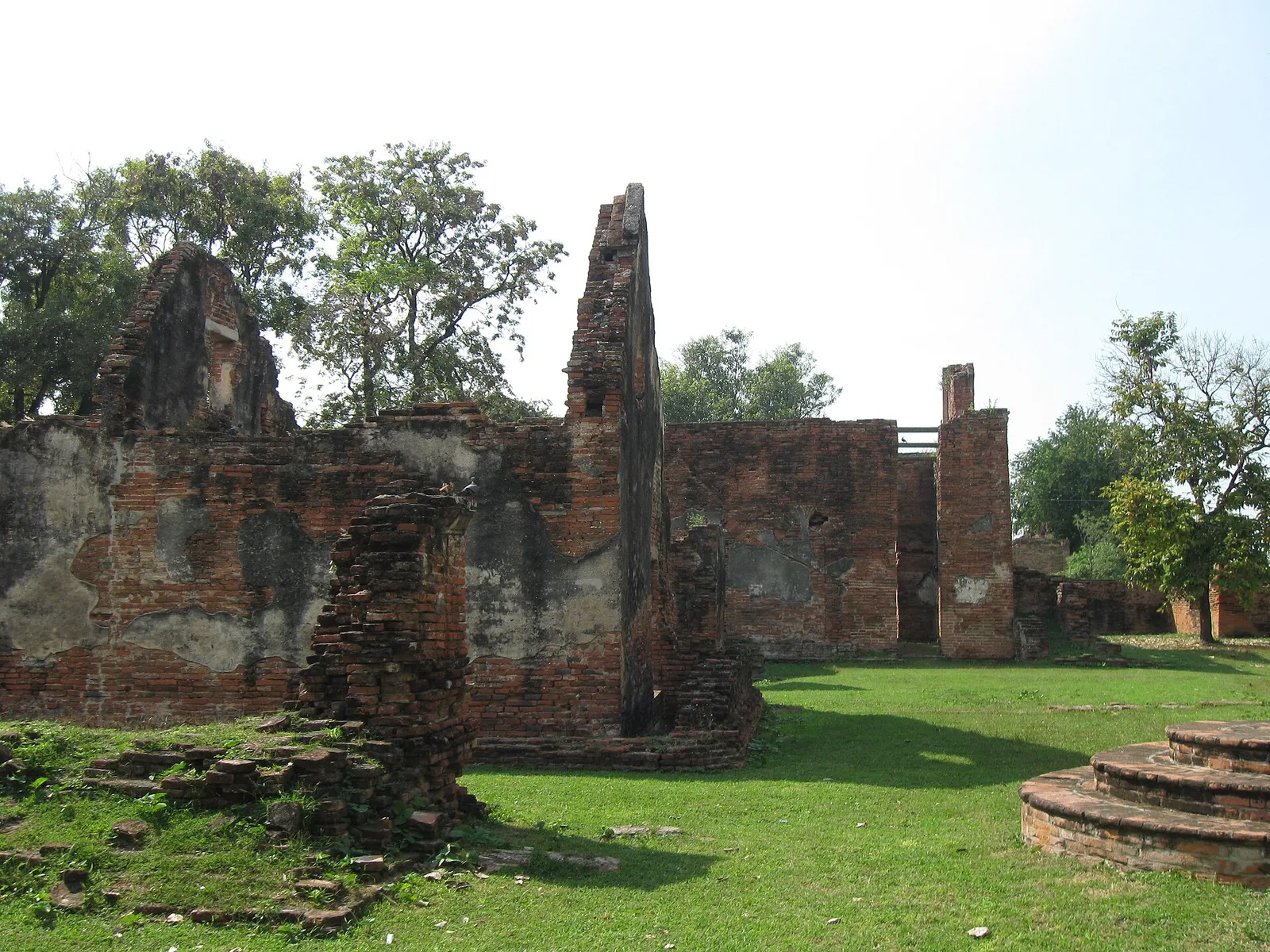 ซากอาคารและผนังสูงหลายชั้นในบ้านวิชาเยนทร์ ล้อมด้วยลานหญ้า