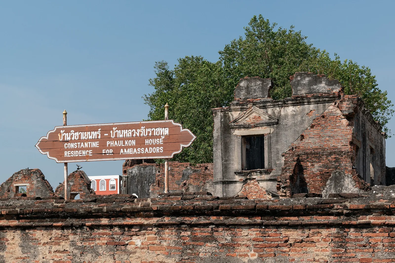 ป้ายชื่อบ้านวิชาเยนทร์–บ้านหลวงรับราชทูต ภาษาไทยและอังกฤษ หน้ากำแพงอิฐและซากอาคาร