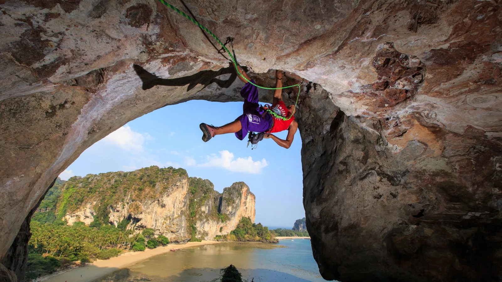 นักปีนผาบนเพดานหน้าผาหินปูนริมทะเล มองเห็นชายหาดและเขาหินปูน ภาพประกอบข่าวรางวัลเกาะและชายหาดของ ททท.