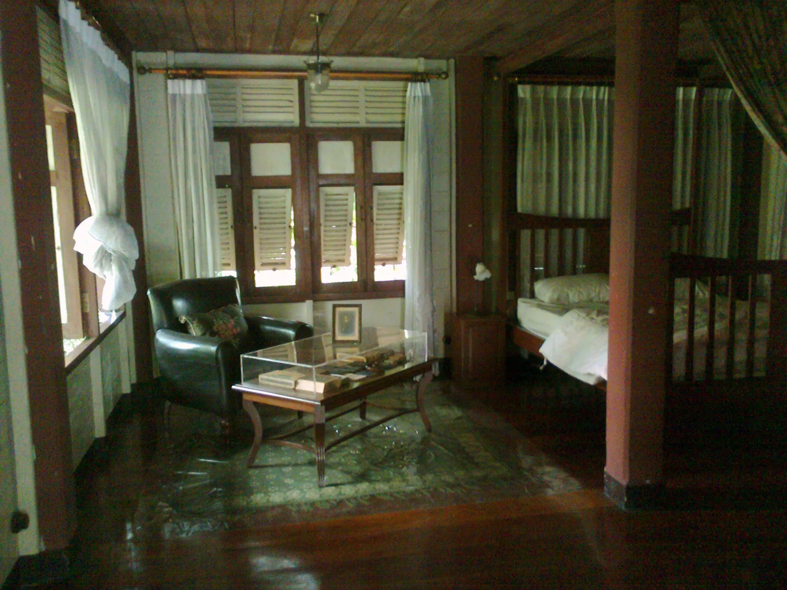 ห้องที่มีเก้าอี้หนัง โต๊ะกระจก และเตียงนอน พื้นไม้ขัดเงา ในพิพิธภัณฑ์ชาวบางกอก
