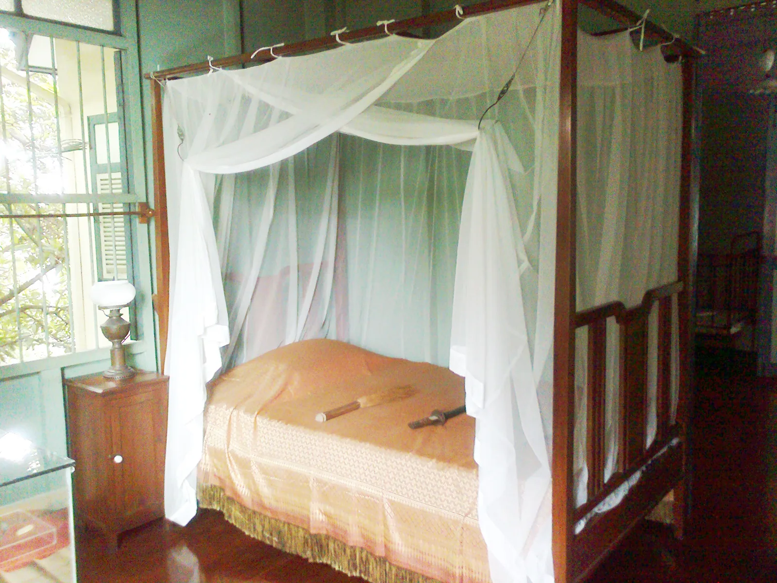 เตียงไม้เสามุ้งกางมุ้งสีขาวในห้องนอนชั้นบนของพิพิธภัณฑ์ชาวบางกอก