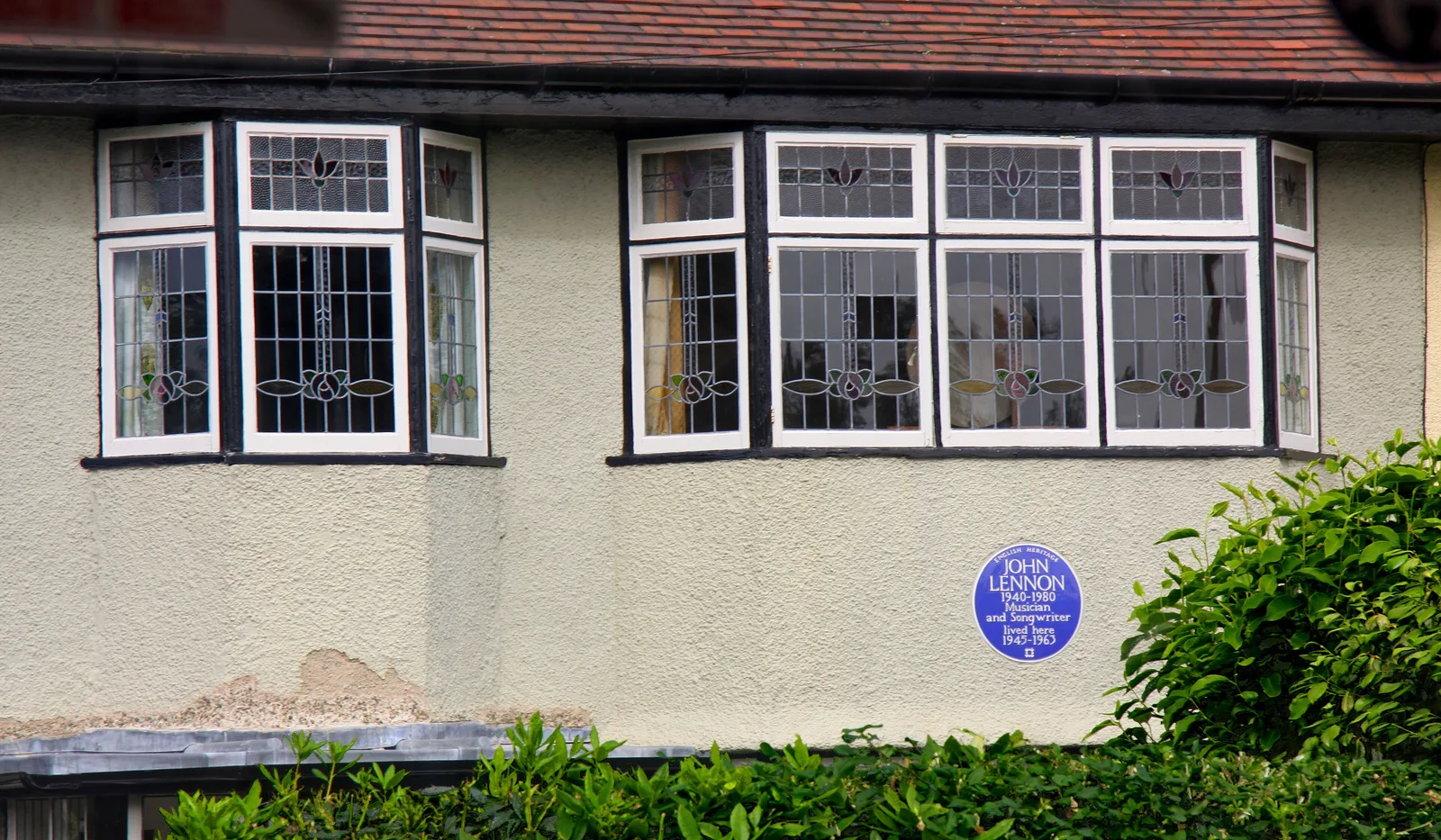 หน้าต่างกระจกสีกรอบตะกั่วชั้นบนของ Mendips และแผ่นป้ายสีน้ำเงินของ English Heritage ที่ระบุชื่อ John Lennon