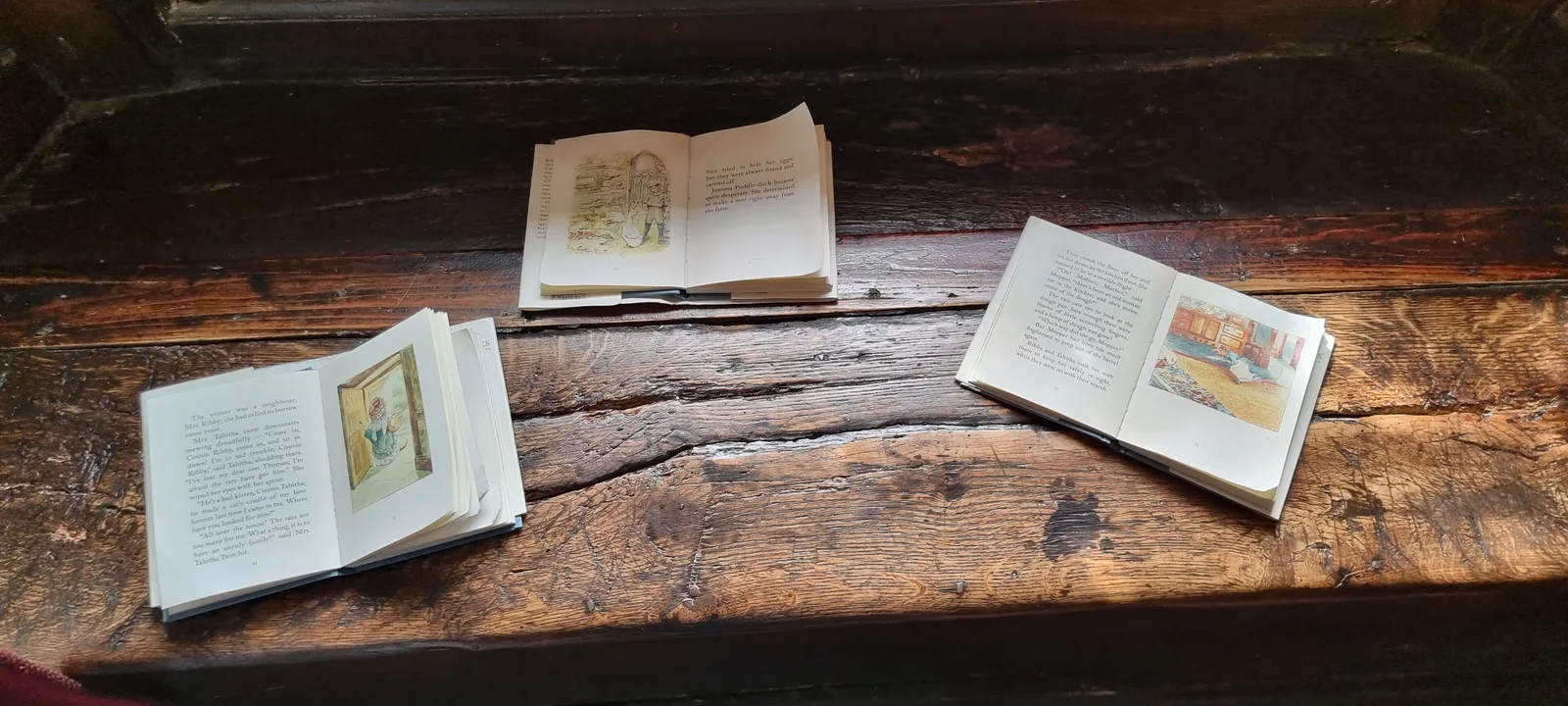 หนังสือนิทานเปิดวางบนโต๊ะไม้ภายใน Hill Top ภาพถ่ายเมื่อ 13 กรกฎาคม 2022
