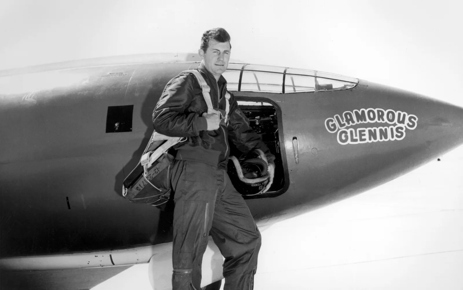 Chuck Yeager ยืนข้างห้องนักบินของเครื่องบิน Bell X-1 ลำที่ 1 ที่มีชื่อ Glamorous Glennis เขียนไว้บนหัวเครื่อง