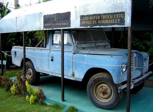 รถกระบะ Land Rover สีฟ้าที่จัดแสดงใต้หลังคาในบริเวณ Bob Marley Museum พร้อมป้ายระบุว่าเป็นรถปี 1976 ที่ Bob Marley เป็นเจ้าของ