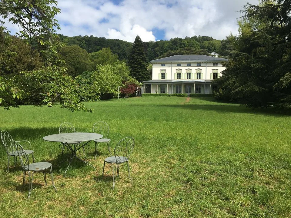 สนามหญ้ากว้างหน้า Manoir de Ban กับโต๊ะและเก้าอี้ในสวน ภาพจาก Chaplin's World