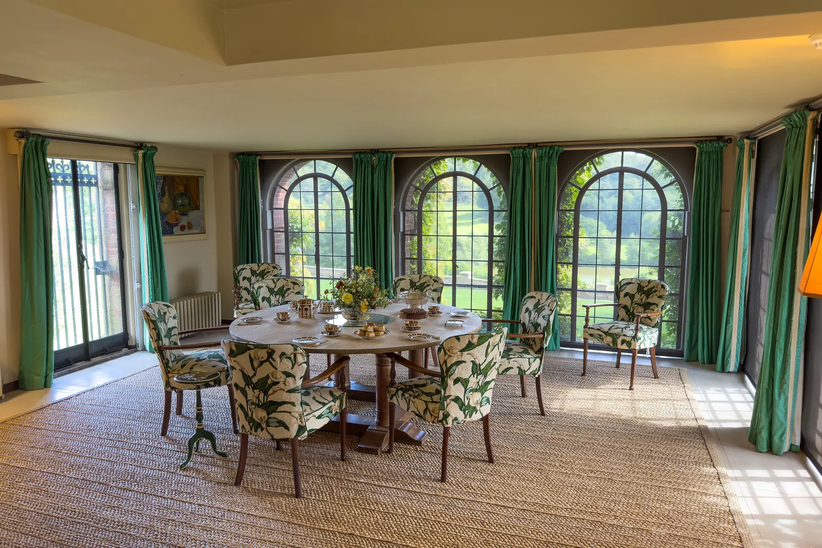 ห้องอาหาร (Dining Room) ของบ้าน Chartwell โต๊ะกลมกับเก้าอี้หุ้มผ้าลายดอก หน้าต่างโค้งหลายบาน และผ้าม่านสีเขียว ภาพถ่ายเมื่อ 8 กันยายน 2025